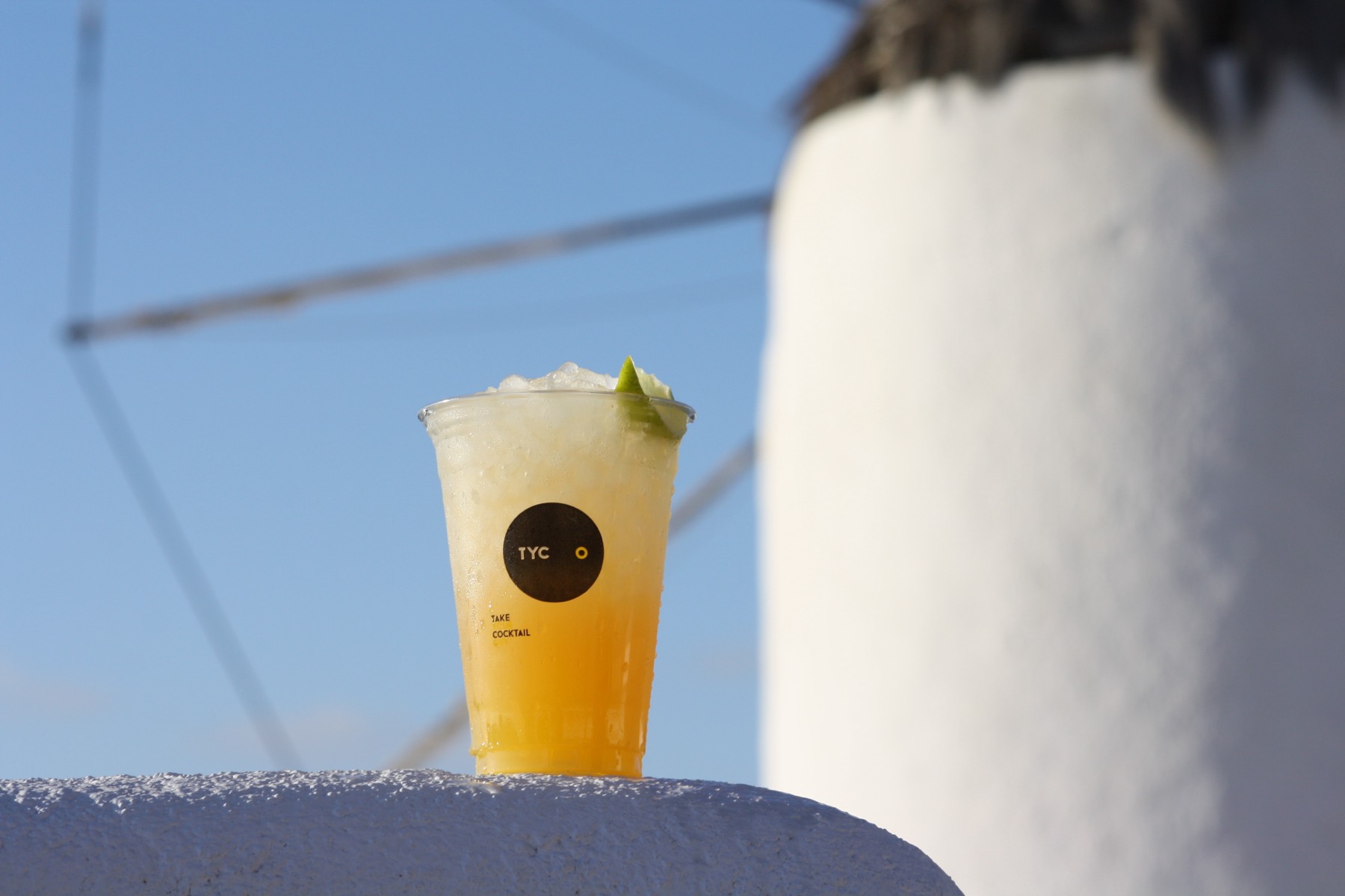 A TYCO cocktail held up against the Mykonos sky